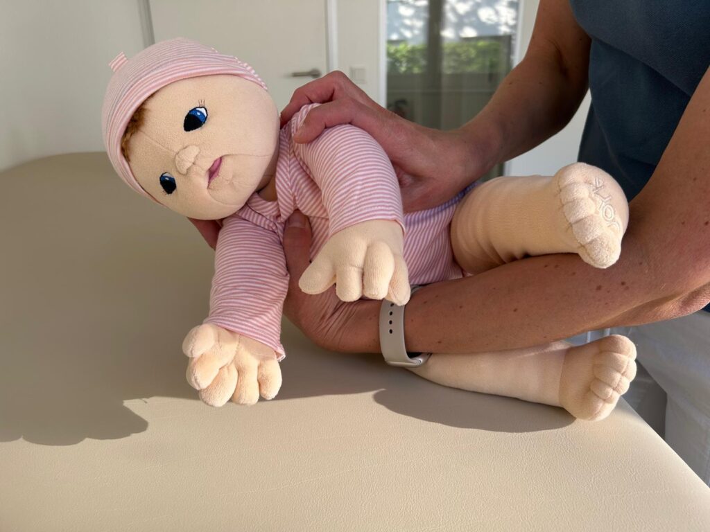 Sanftes Herunterlegen eines Babys über das Becken in die Seitenlage – Anleitung zur rückenfreundlichen Umlagerung in der Kinderphysiotherapie Ritterburg