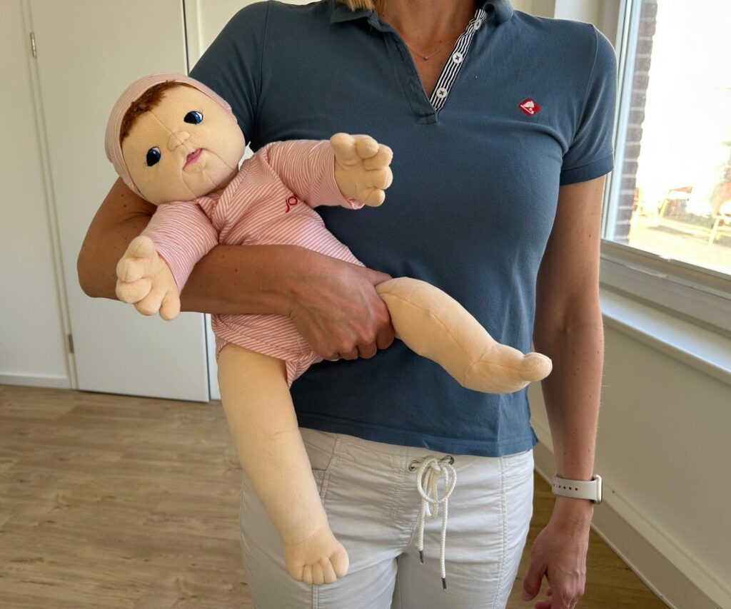 Tragen eines Babys in Seitenlage ab dem 3. Monat – ergonomische und entwicklungsfördernde Position, demonstriert in der Kinderphysiotherapie Ritterburg