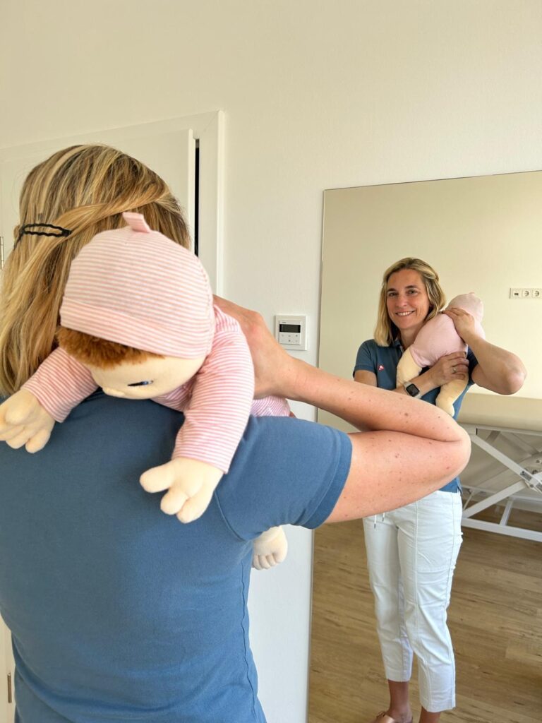 Trageposition über der Schulter zur Unterstützung des Bäuerchens beim Baby – demonstriert mit Puppe in der Kinderphysiotherapie Ritterburg
