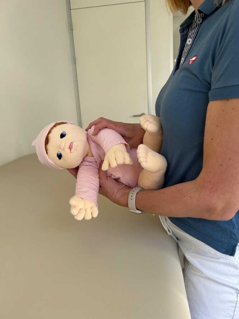 Hochnehmen eines Babys aus der Seitenlage mit sicherer Armführung – gezeigte Handling-Technik in der Kinderphysiotherapie Ritterburg