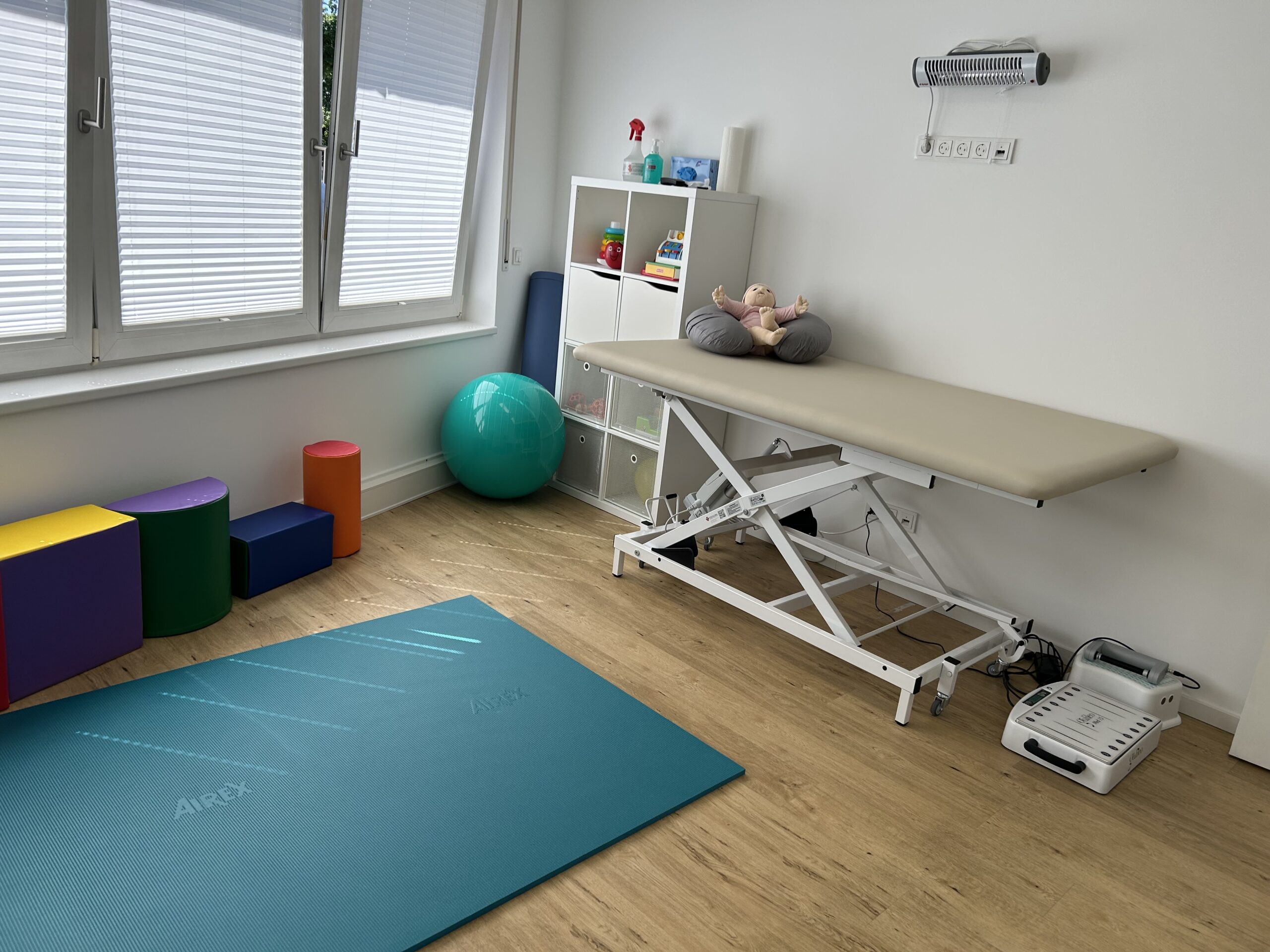 Behandlungsraum der Kinderphysiotherapie Ritterburg in Münster mit Therapieliege, Gymnastikmatte, Pezziball und bunten Therapieelementen für Säuglings- und Kindertherapie