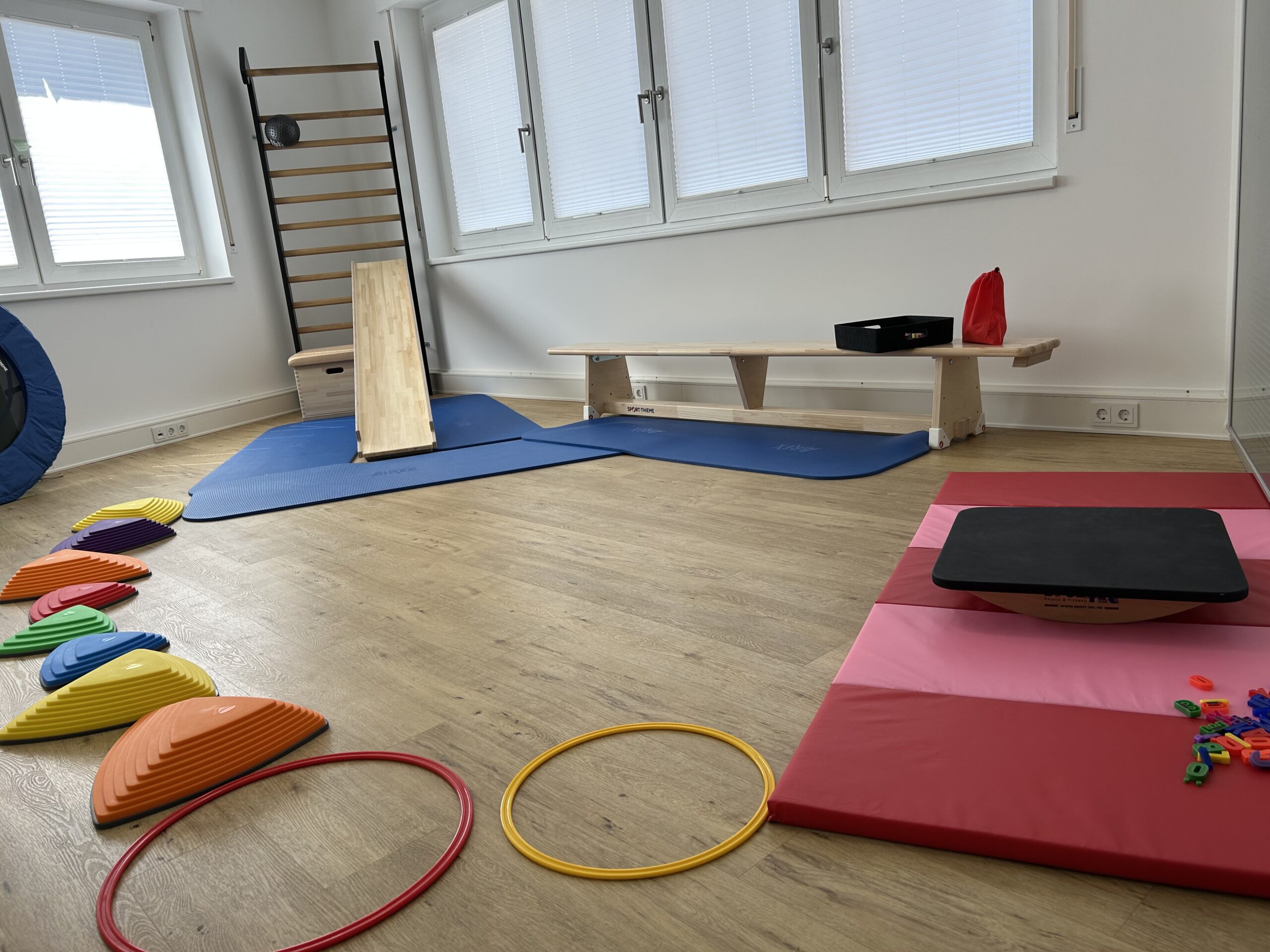 Therapieraum der Kinderphysiotherapie Ritterburg in Münster mit Balancierstrecke, Sprossenwand, Rutsche und Motorikmaterial zur Förderung von Gleichgewicht und Koordination